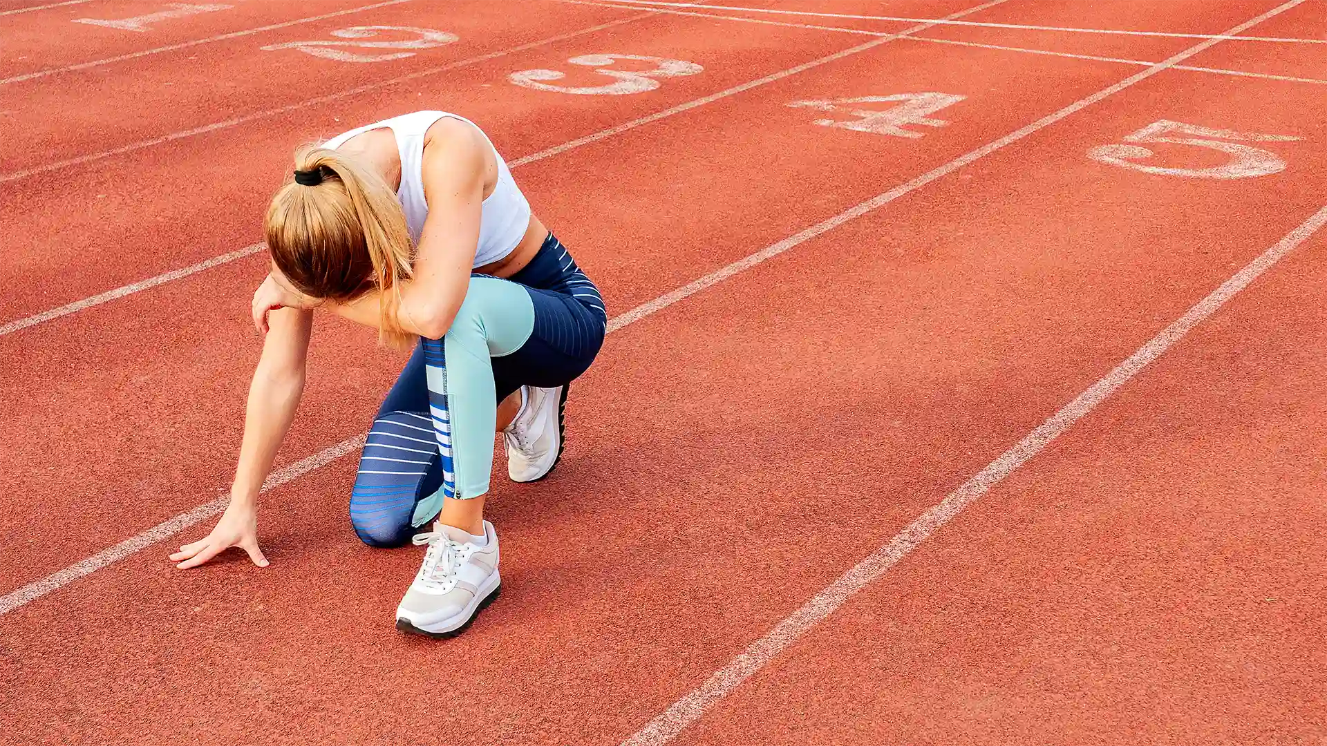 Zmęczona sportsmenka na bieżni lekkoatletycznej – objawy hipoglikemii reaktywnej u osób aktywnych fizycznie