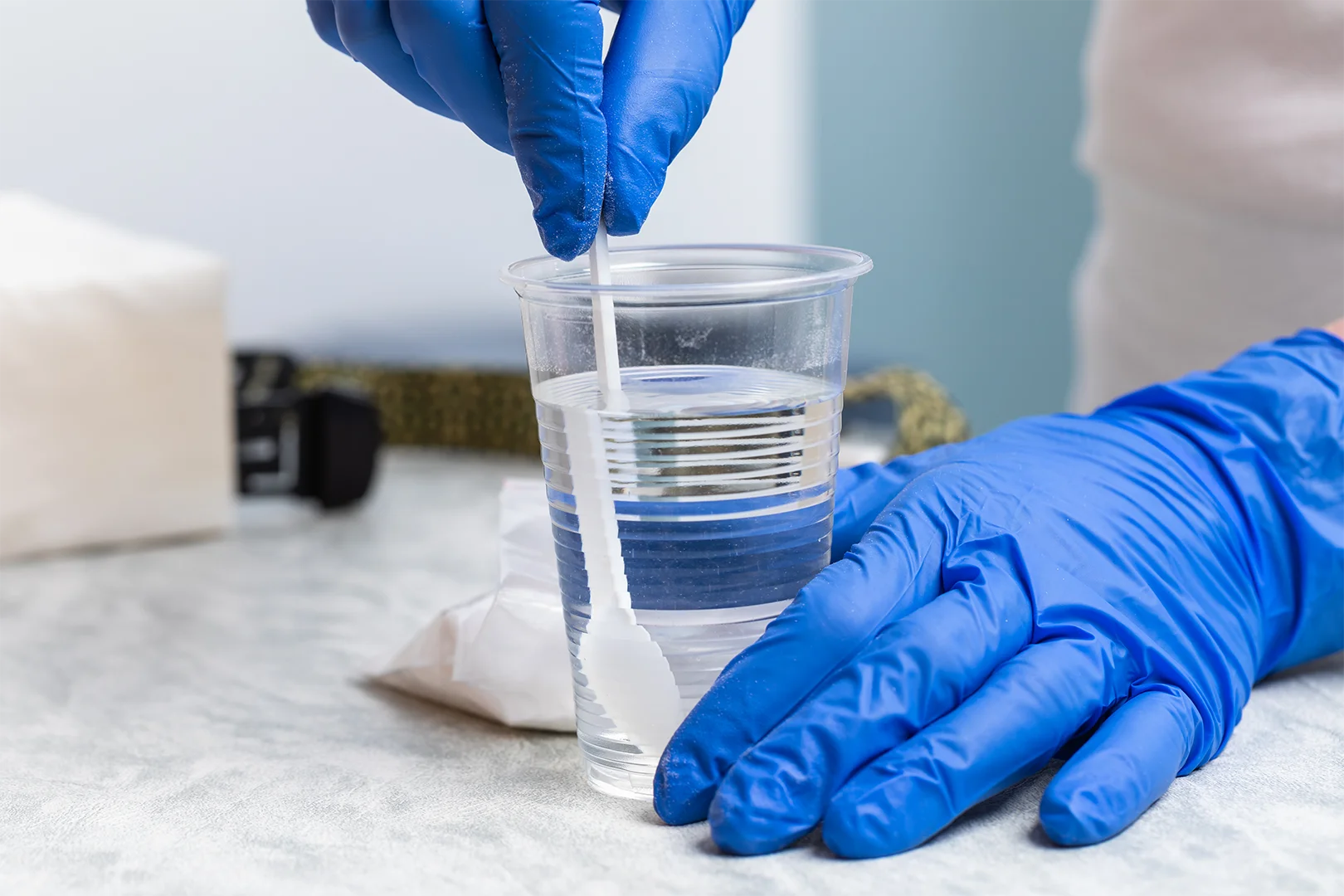 Test obciążenia glukozą OGTT – plastikowy kubek z wodą i proszkiem glukozy przygotowywany do badania diagnostycznego hipoglikemii reaktywnej